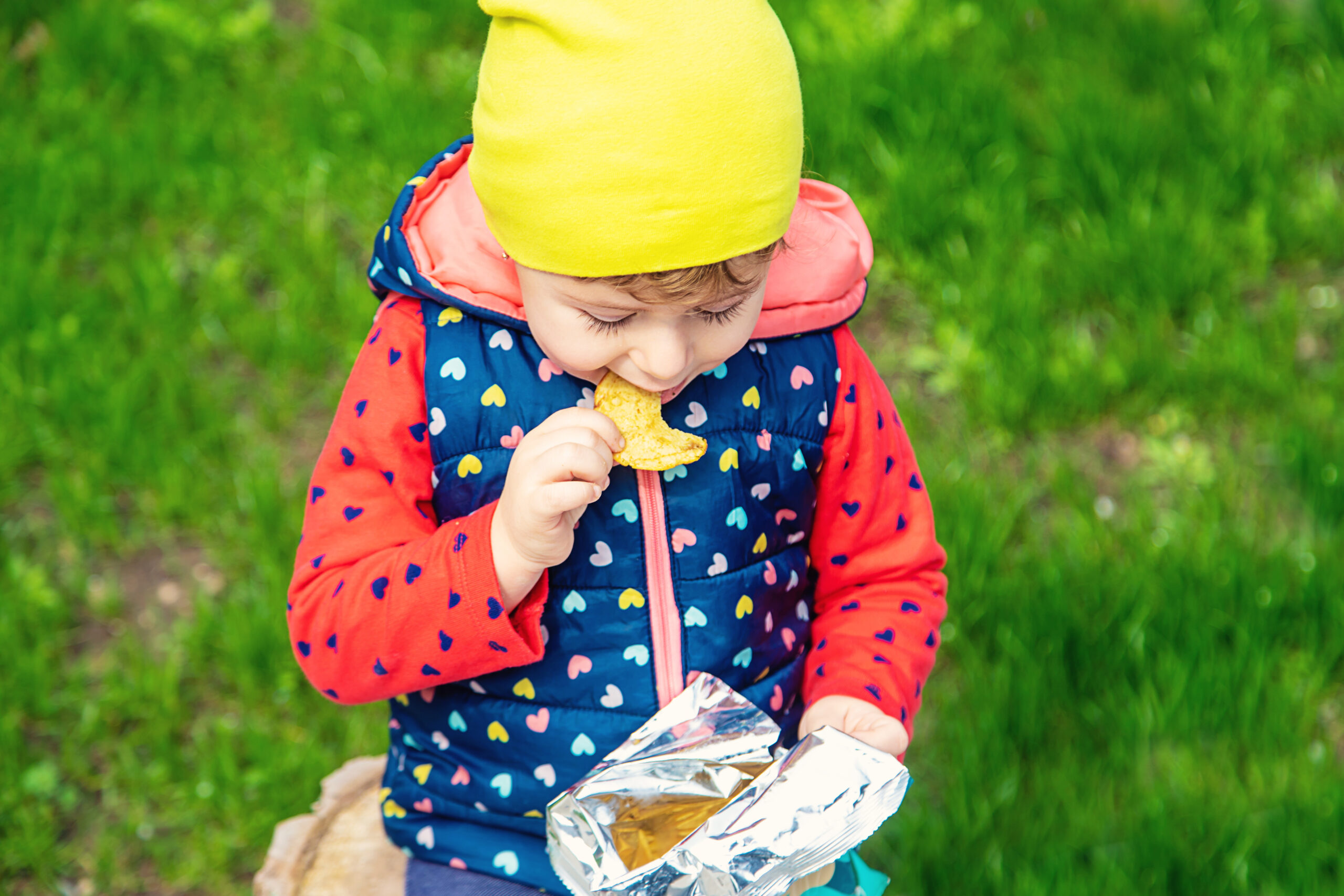 The child eats chips in the park. Selective focus