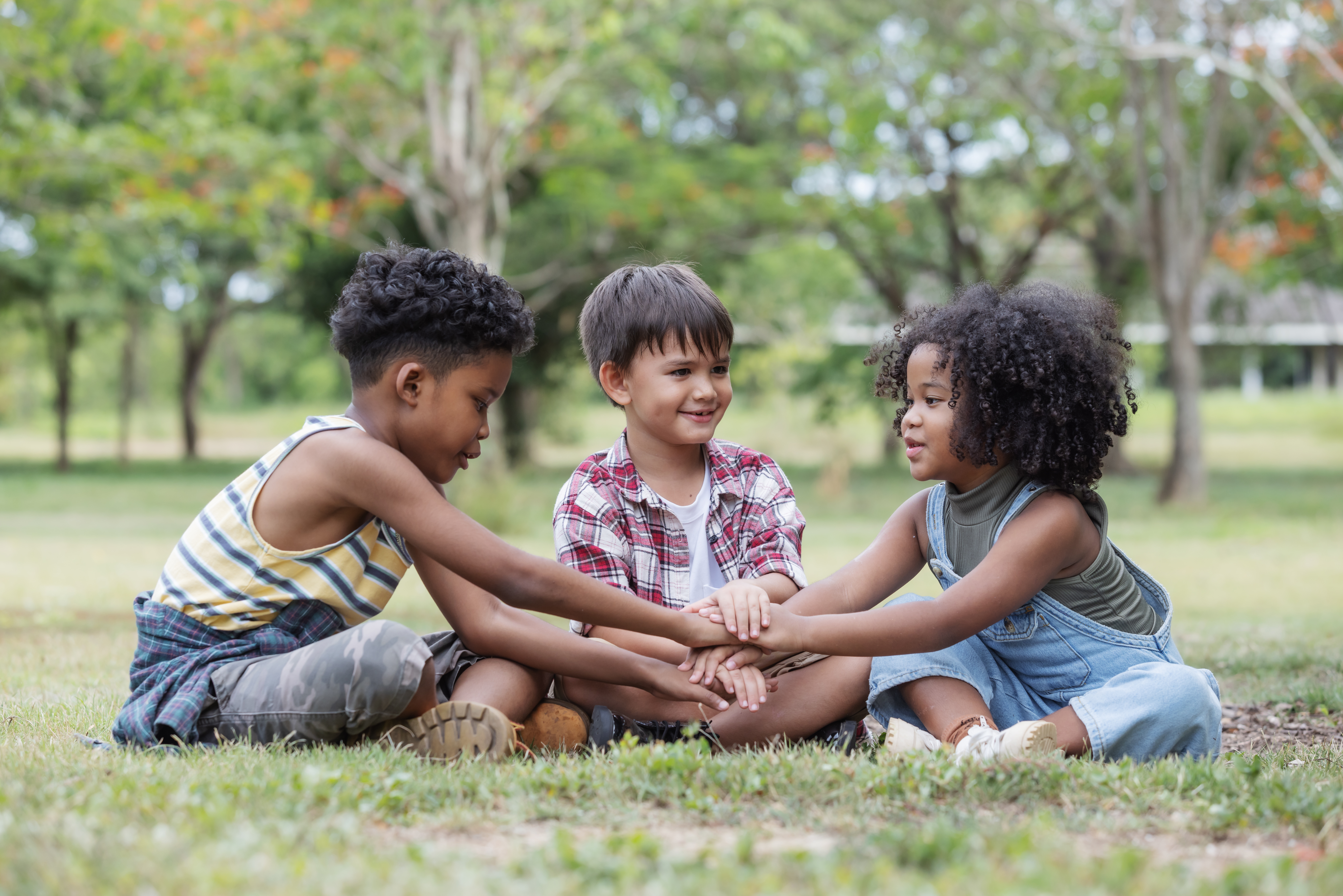 three-multi-ethnic-children-sit-on-the-grass-in-a-2025-02-13-18-03-43-utc