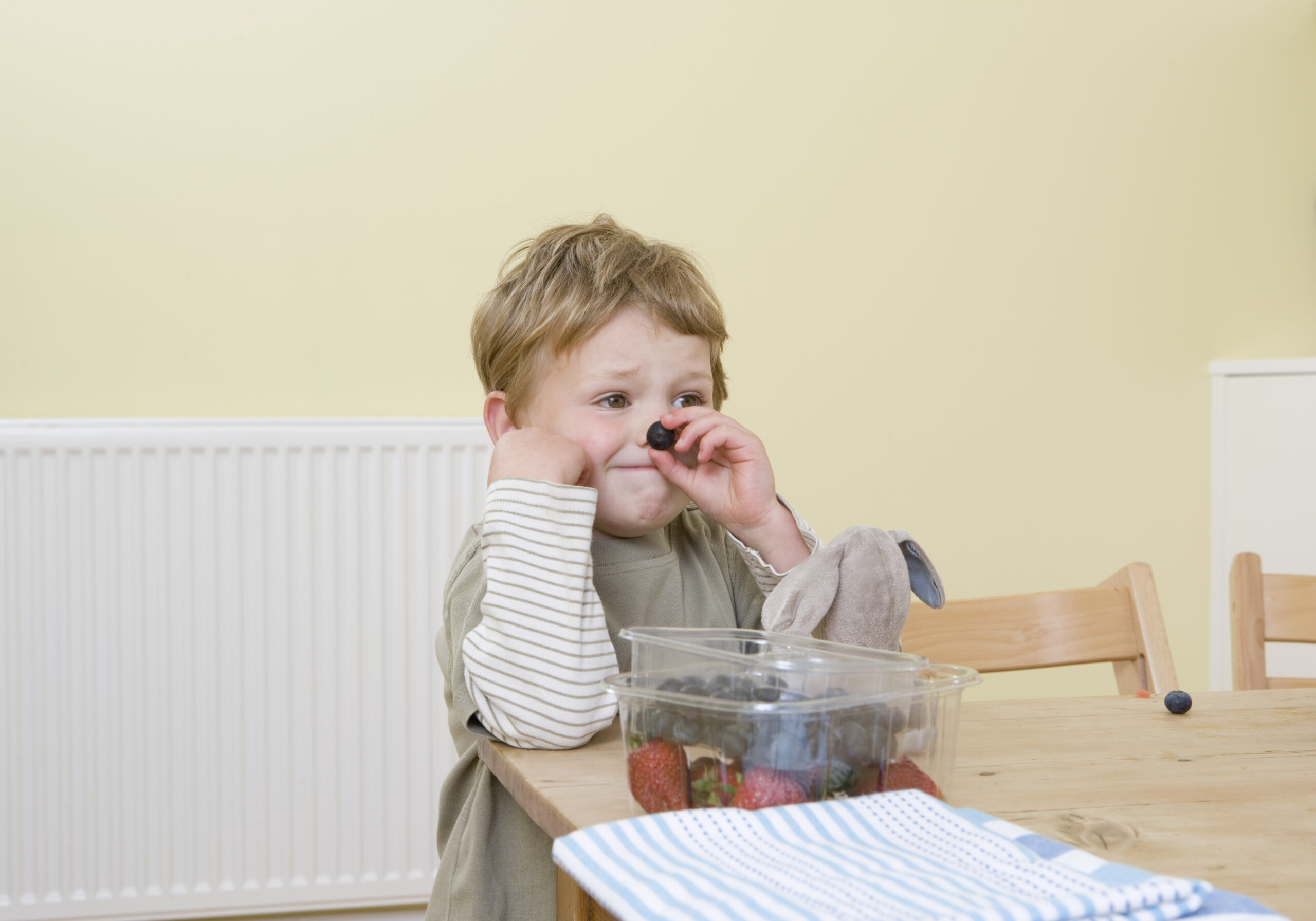 boy holding berry on nose